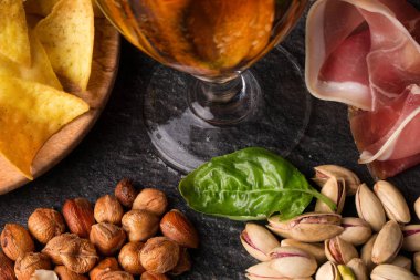 Yukarıdan görünüm klasik içindekiler hakkında. Light bira, baharatlı cips, fındık ve antep fıstığı, sağlıklı fesleğen ve dilimlenmiş et siyah bir taş üzerinde arka plan masa. Close-Up aperatifler bar. 
