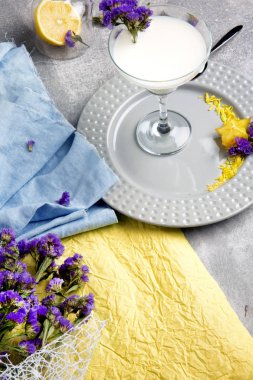 Güzel bir kompozisyon şeffaf cam masa lambası arka plan üzerinde beyaz kokteyl ve çok renkli kumaş dolu. Organik vejetaryen süt yüzlü çiçekler ve limon ile. 