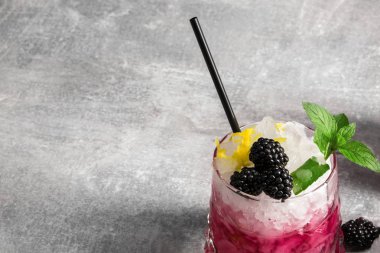 Buz küpleri, böğürtlen ve nane, saman içme bir ışık gri arka plan üzerinde siyah yeşil taze yaprakları yaz soğuk meyve kokteyl Close-Up.