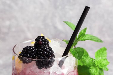 Buz küpleri, böğürtlen ve nane, saman içme bir ışık gri arka plan üzerinde siyah yeşil taze yaprakları yaz soğuk meyve kokteyl Close-Up.