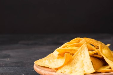 Altın cips cips parlak ahşap masa üzerinde bir yakın çekim resim. Baharatlı lezzetli aperatifler alkollü içecekler için. Meksika geleneksel meze doygun siyah taş zemin. Kopya alanı.