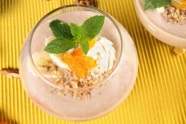 Top dondurma, muz, Kuru Kayısı ve nane yaprakları parlak sarı bir arka plan üzerinde meyve içki dolu bir büyük cam görünümünü yakın çekim. Muz milkshake. Vegan smoothies kavramı.