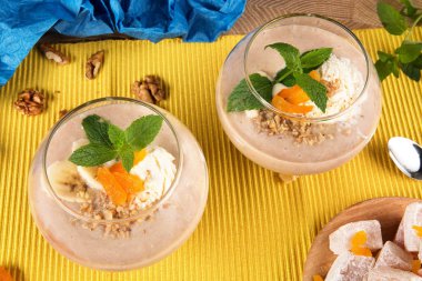 Üstten Görünüm iki muz smoothies ile Türk Lokumu, Kuru Kayısı, ceviz ve kaşık çok renkli arka plan üzerinde büyük bir gözlük. Tatlılar ile sağlıklı güler yüzlü. ve meyveler, yakın çekim.