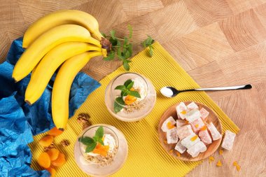 Olgun muz parlak kompozisyonu bir görünümde yukarıdan, meyve tatlı gözlük, Türk lokumu ahşap plaka, Kuru Kayısı, ceviz, dondurma ve ahşap bir arka plan üzerine nane yaprakları..