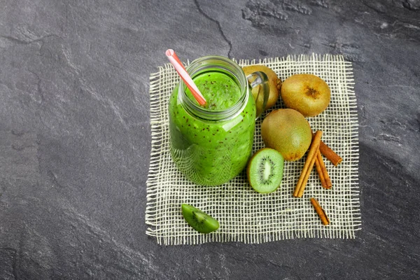 Yukarıdan bir görünümü temel bir mason kavanoza kivi yoğurt ve kumaş siyah bir arka plan üzerinde doğal maddeler. Kivi meyve yığını yanında dekoratif aromatik tarçın. Kopya alanı.