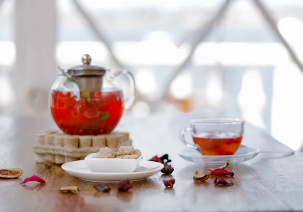 レストランで木製のテーブルの赤スグリとイチゴ紅茶の完全透明ティーポットの入札の組成物 背景をぼかした写真のスパイスを赤の果実飲料 有機の飲み物 — ストック写真