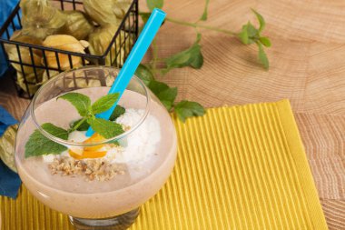 Büyük tatlı bardağın dolu meyve yüzlü dondurma, muz, Kuru Kayısı ve nane yaprakları parlak sarı bir arka plan üzerinde Close-Up. Muz milkshake. Vegan smoothies kavramı.