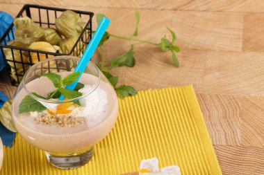 Büyük tatlı bardağın dolu meyve yüzlü dondurma, muz, Kuru Kayısı ve nane yaprakları parlak sarı bir arka plan üzerinde Close-Up. Muz milkshake. Vegan smoothies kavramı.