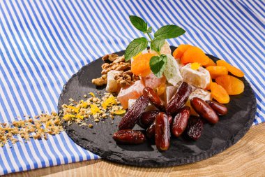 Türk Lokumu, lokum veya rahat lokum tarihi meyve, ceviz ve canlı taze nane yaprakları çizgili bir arka plan üzerinde çizgili bir masa örtüsü üzerinde bir cam tabakta closeup.