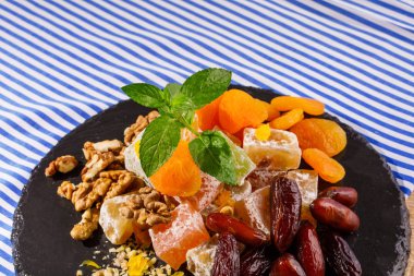 Türk Lokumu, vekil veya rahat lokum, ceviz, tarihi meyve veya tarihleri ve canlı nane yaprakları çizgili bir arka plan üzerine bir cam plaka Close-Up.