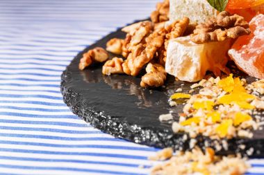 Türk Lokumu, lokum veya rahat lokum, ceviz ve nane canlı yeşil yaprakları çizgili bir arka plan üzerinde koyu cam tabakta güzel bir kompozisyon yakın çekim. Tatlılar kavramı. Kopya alanı.