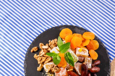 Türk Lokumu, lokum veya rahat lokum, Kuru Kayısı, tatlı tarihi meyve, ceviz closeup, parlak aromatik nane çizgili bir arka plan üzerinde bırakır. Tatlılar Üstten Görünüm.