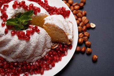 Üstten Görünüm şeker tozu sosu, kırmızı nar taneleri ve aromatik nane yaprakları ile beyaz mermer kek. Ev yapımı kek mor bir arka plan üzerine bir tabak. Klasik pasta tarifleri kavramı.