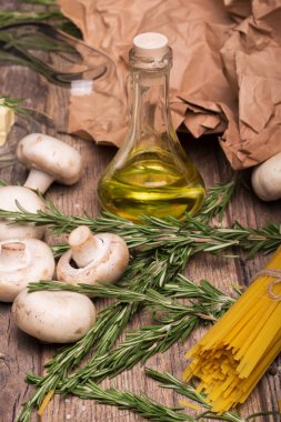 Güzel kokulu biberiye twigs, İtalyan makarna ve ahşap masa arka plan üzerinde mantar. Pişirme kavramı.