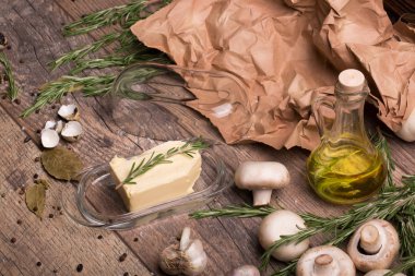 ahşap masa arka plan üzerinde üstten görünüm bir cam kapta tereyağı. Yumurta kabuğu ve mantar. Zeytinyağı yanındaki bir pişirme kağıdı ile Rosemary çırpı. Lezzetli yemek. Gıda kavramı.