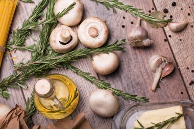 Güzel kokulu biberiye twigs, İtalyan makarna ve ahşap masa arka plan üzerinde mantar. Pişirme kavramı.