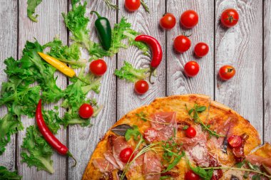 Masa lambası arka plan üzerinde üstten görünüm taze roka yeşillik ve küçük biber dilimlenmiş, geleneksel margherita pizza. Et ve sebze besleyici pizza. Yemek hazırlama kavramı.