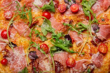 Besleyici maddeler ile çok renkli parlak pizza bir makro resim. Roka ve otlar, dilimlenmiş domates, baharatlı fesleğen ve Klasik peynir pizza. Geleneksel İtalyan yemeği kavramı.