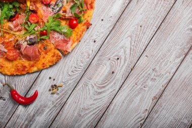 Makro resim rustik masa arka plan üzerinde parlak yemeğin. Kırmızı sıcak biber biber lezzetli salam pizzayla bir görünüm yukarıdan. İtalyan mutfağı. Yemek, pişirme kavramı. Kopya alanı.