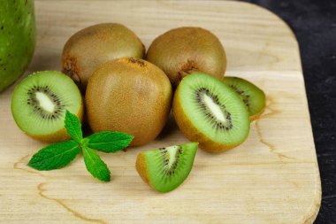 Tam ve yarım kivi ahşap masa lambası üzerinde kesim taze bir yığın closeup. Dilim kazıklı özlü kivi lezzetli kivi ahşap masa lambası üzerinde. Bir egzotik yaz meyve.