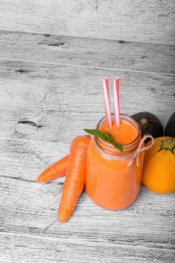 Bir mason kavanoza bir serinletici karışık içecek tam bir görünüm yukarıdan. Payet gri tablo arka plan üzerinde bir detoks havuç güler yüzlü içki. Sulu bir kokteyl olgun havuç tüpler yanında. Kopya alanı.