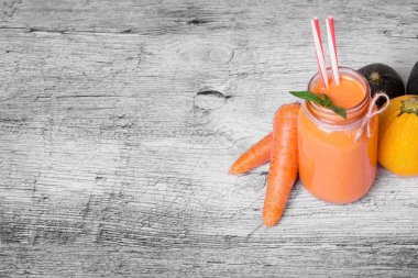 Ferah ışık gri arka plan üzerinde Besleyici bir sebze içecek bir cam şişe. Soyulmuş havuç ve çok renkli kabakları bir tablo. Kahvaltı için taze nane ile portakal suyu. Kopya alanı.
