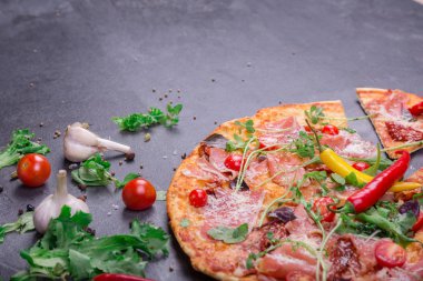 İştah açıcı biberli pizza et, kırmızı sıcak biber biber ve karanlık bir taş zemin üzerine fesleğen ile fotoğrafı yakın çekim. 