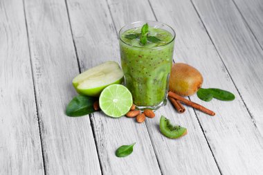 gri bir ahşap zemin üzerine cam yüzlü kivi, elma ve limon nane ile Üstten Görünüm.