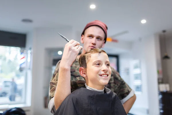 Friseur Friseur Parihopher strechot kleiner Junge sitzt auf einem Stuhl — Stockfoto
