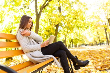 Kız sonbahar bir arka plan üzerinde beyaz bir ceket