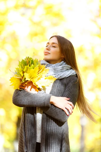 Dziewczyna w czarnym płaszczu, na tle jesieni z liści — Zdjęcie stockowe