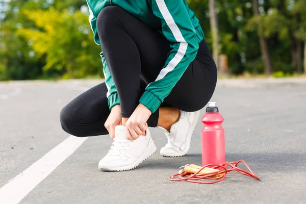 Genç bir sportif kadın spor ayakkabı bağcıkları bağları. Mükemmel vücut egzersizleri yapıyor bir kızla. — Stok fotoğraf
