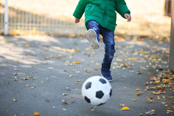 Menino brincando com uma bola no outono na rua — Fotografia de Stock