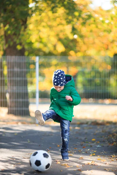 Junge spielt im Herbst auf der Straße mit einem Ball — Stockfoto