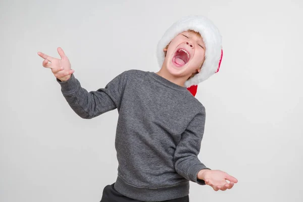 Emotionele blond jongetje in een feestelijke rode hoed. Kleine Kerstman. — Stockfoto