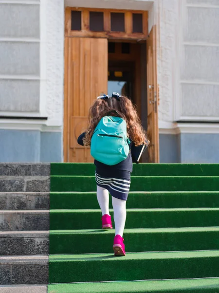 Het meisje gaat naar school met een koffertje en een boek — Stockfoto