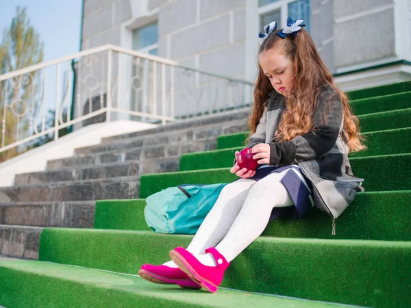 Flickan går till skolan med en portfölj och böcker — Stockfoto