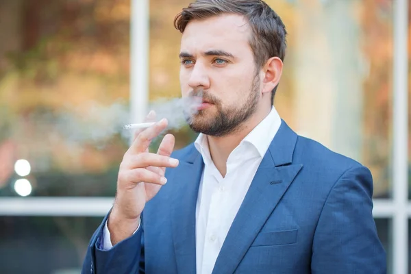 Un homme d'affaires avec barbe fumant de la cigarette dans la rue . — Photo