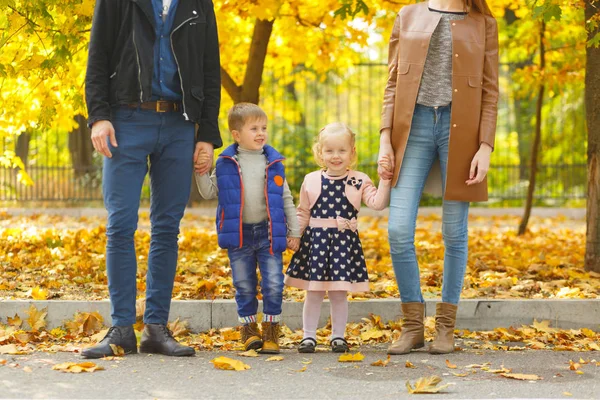 Familia, infancia, concepto de amor. Familia feliz jugando con hojas de otoño en el parque. Vacaciones familiares. Mamá y papá con niños . —  Fotos de Stock