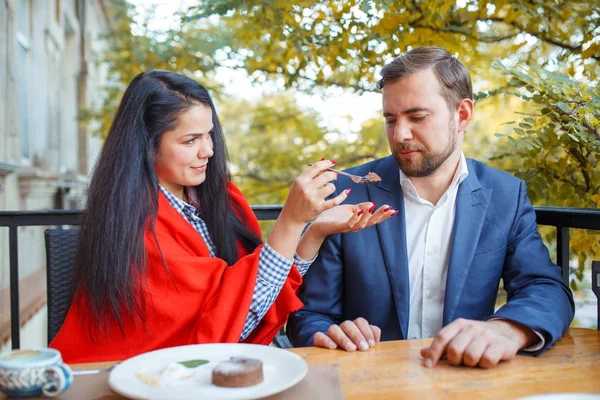 Mladý pár v lásce sedí v kavárně a žena je krmení dort její muž. — Stock fotografie