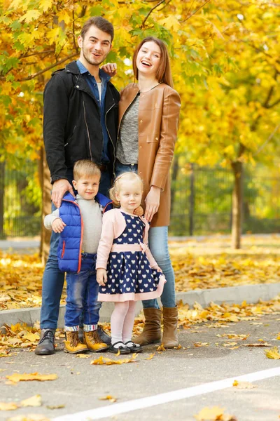 Família, infância, conceito de amor. Família feliz brincando com folhas de outono no parque. Feriados de família. Mãe e pai com filhos . — Fotografia de Stock