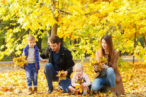 Famille, enfance, concept d'amour. Bonne famille jouant avec les feuilles d'automne dans le parc. Vacances en famille. Maman et papa avec des enfants . — Photo