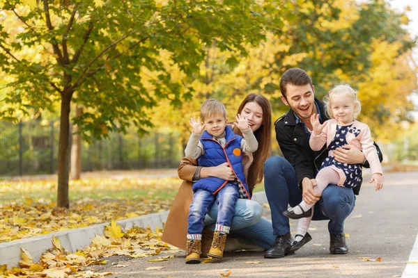 Família, infância, conceito de amor. Família feliz brincando com folhas de outono no parque. Feriados de família. Mãe e pai com filhos . — Fotografia de Stock