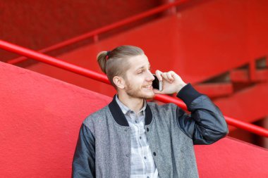 Yakışıklı genç adam açık havada telefonu ile konuşurken.