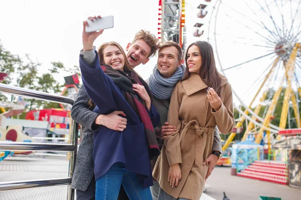 Hermosa compañía joven divirtiéndose y riendo en el parque de atracciones . — Foto de Stock