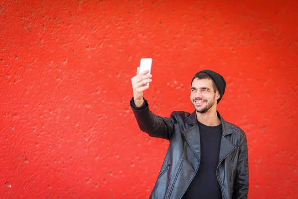 Handsome young man taking photo on a red background. — Stock Photo, Image