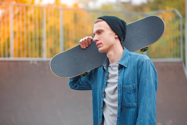 Молодой скейтбордист позирует со скейтбордом в скейтпарке. Концепция . — стоковое фото