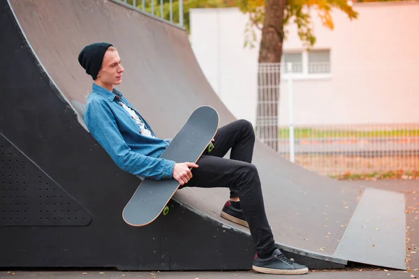 Jovem skatista posando com skate no parque de skate. Conceito de desporto . — Fotografia de Stock