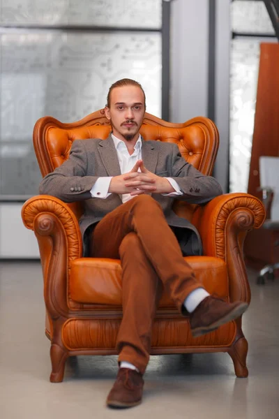 Un hombre feliz en la oficina sentado y posando en la cámara. Concepto empresarial . — Foto de Stock