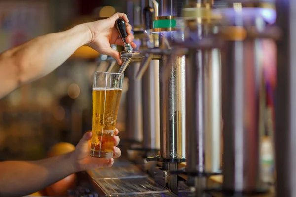 Barman handen gieten een lager bier in een glas. — Stockfoto